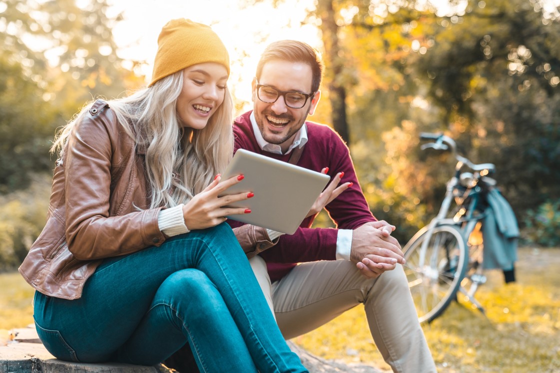 a man and woman sitting on a bench with a laptop