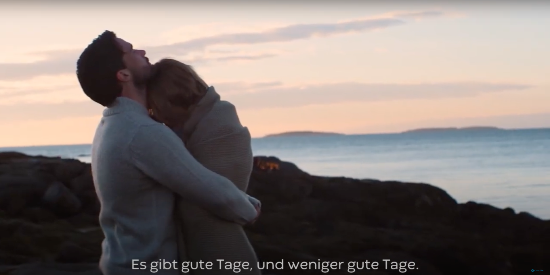 Ein Mann und eine Frau küssen sich an einem felsigen Strand