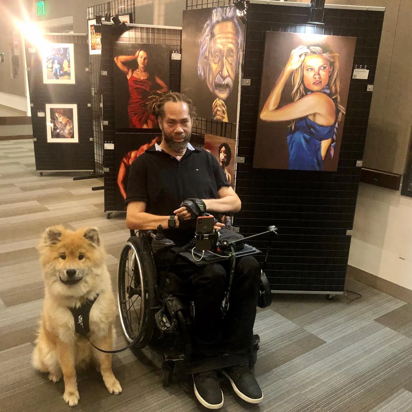 un homme en fauteuil roulant avec un chien devant lui