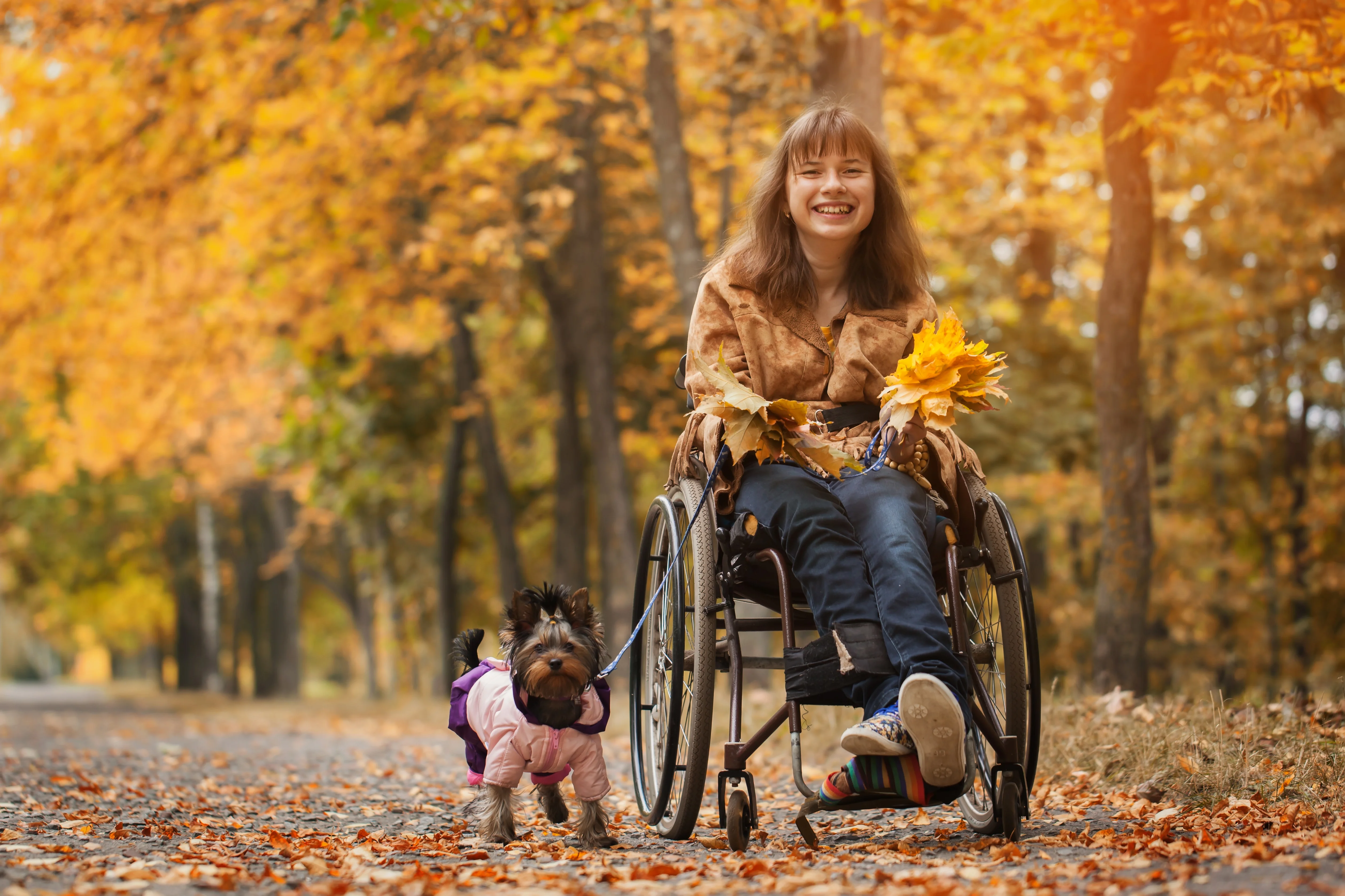 Una mujer en silla de ruedas con un perro en un parque