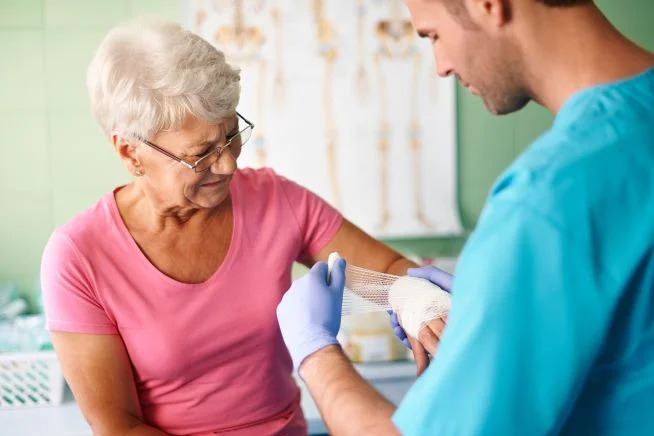 Ein Pfleger verbindet einer Patientin den Arm.