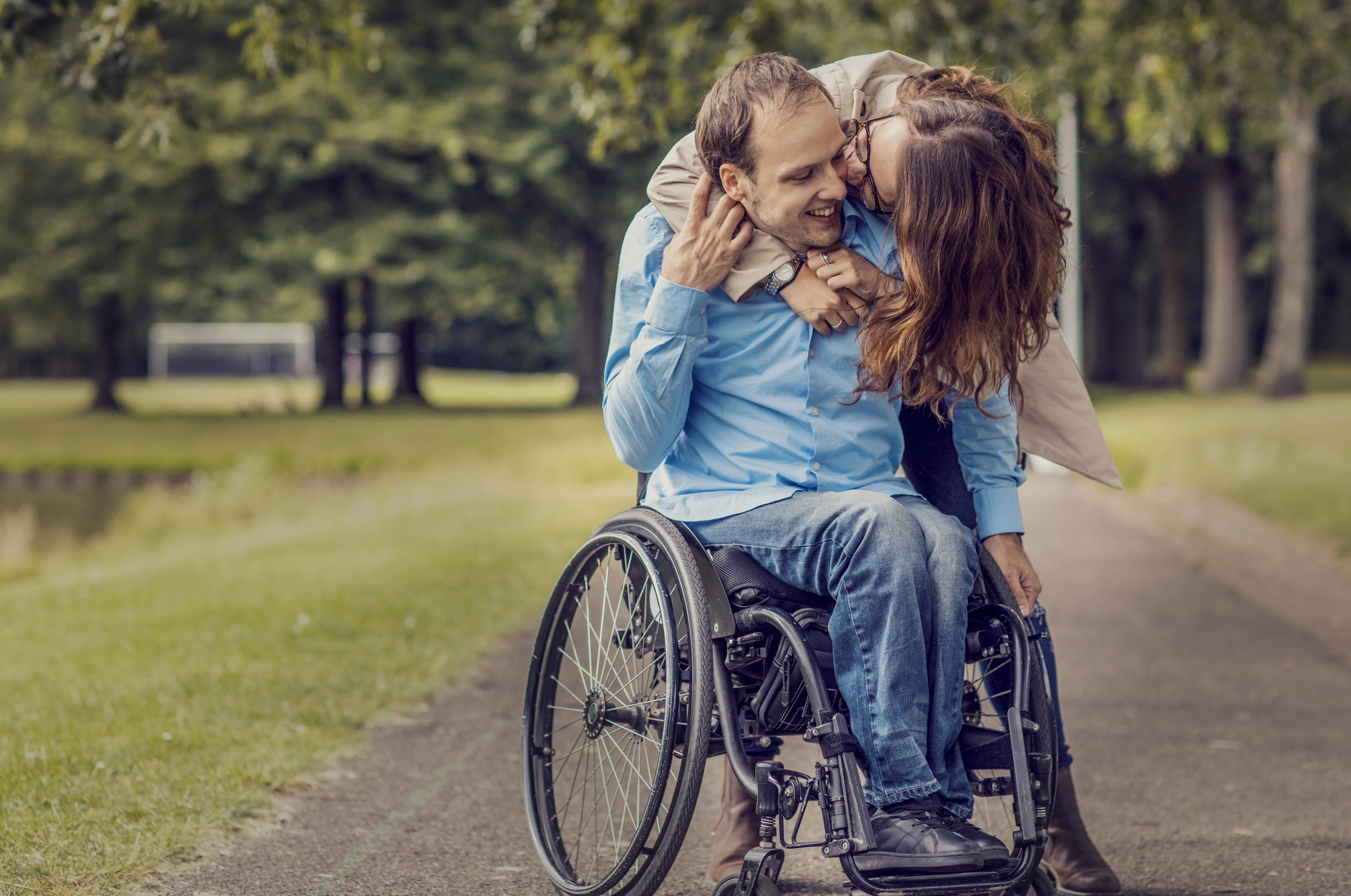 un uomo e una donna che si baciano su una sedia a rotelle