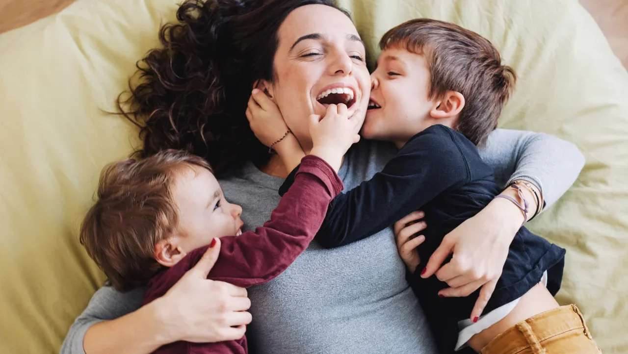 una persona che tiene in braccio una coppia di bambini