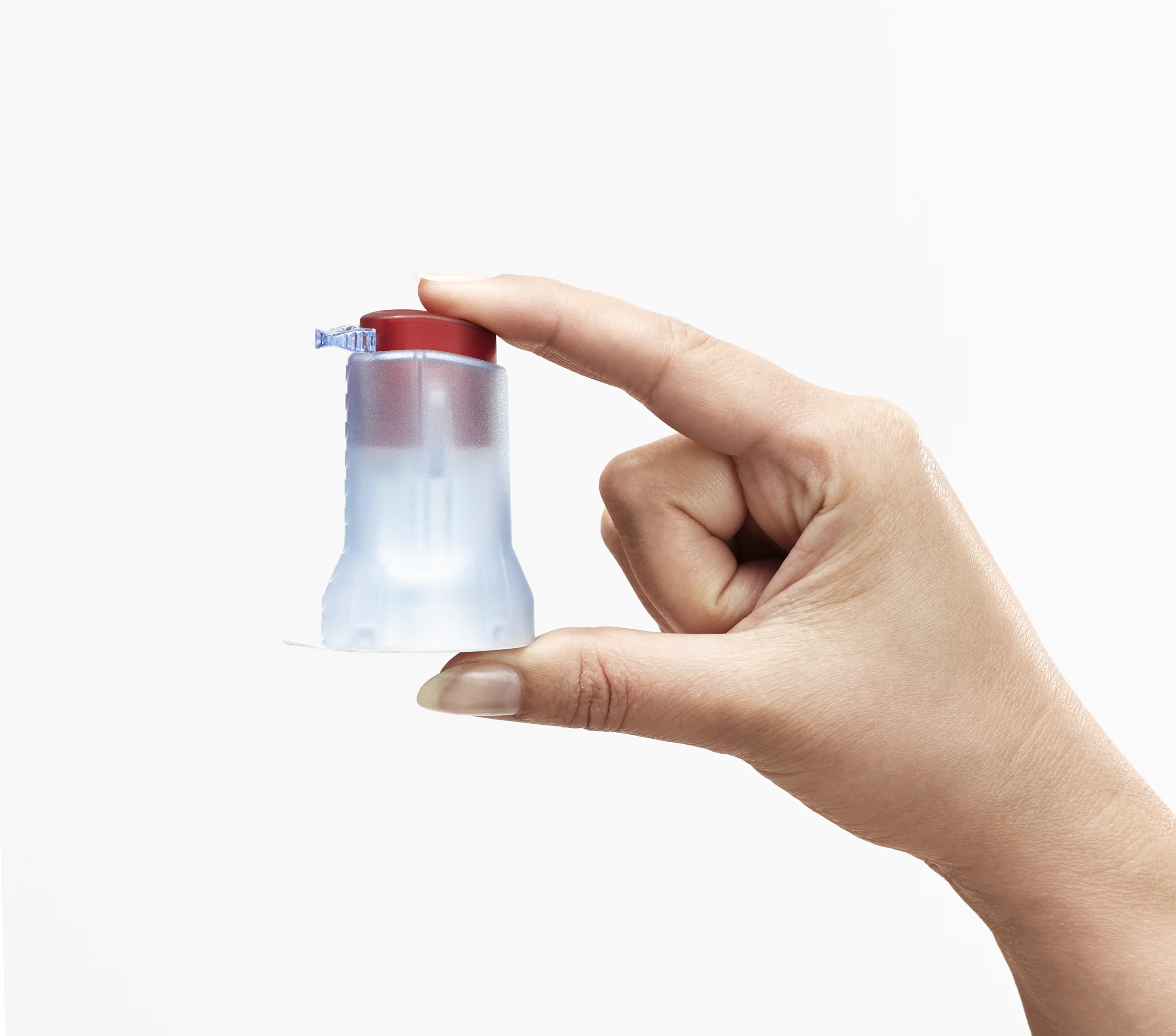 a hand holding a small plastic bottle